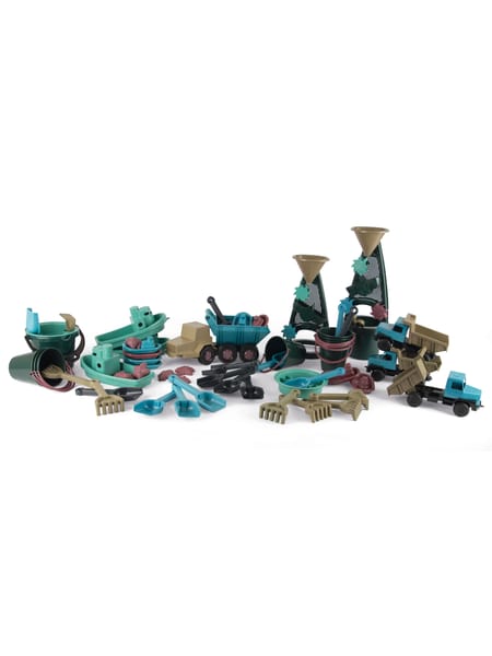 Barn i vinterdress leger med blå vandmølle på sandet jord i skumringen